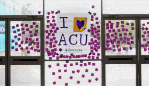 Students stick purple sticky notes on the windows of the Campus Center to thank donors. 